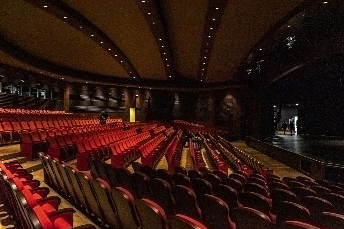 Image of an empty theatre with two figures walking offstage in the top right corner